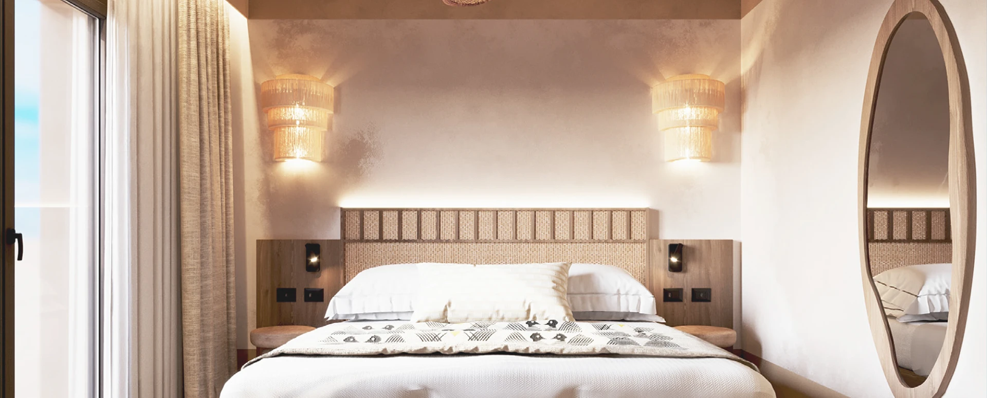 Dettaglio letto matrimoniale con testiera in tessuto e cuscini, comodini in legno e applique laterali.